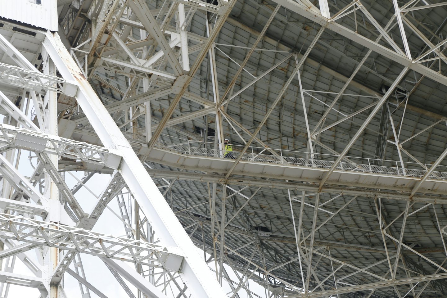 Worker inspects intricate metal framework of large structure.