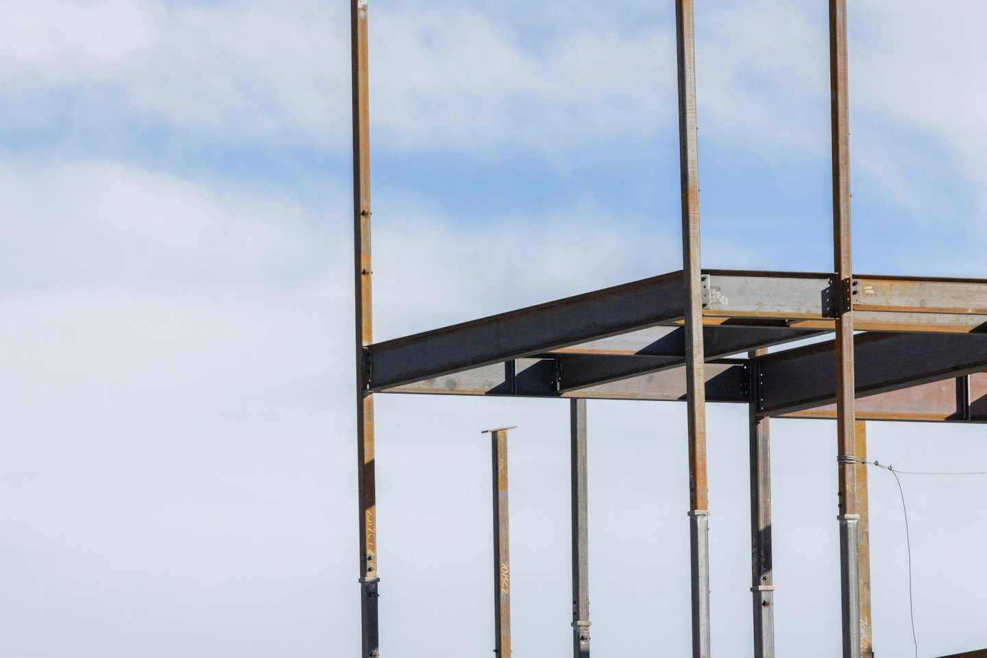 Steel beam framework of a building under construction against blue sky.