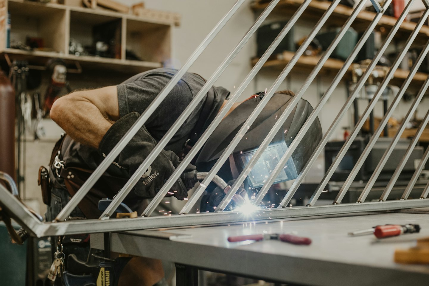 Fabricator welding railing with bright sparks flying.