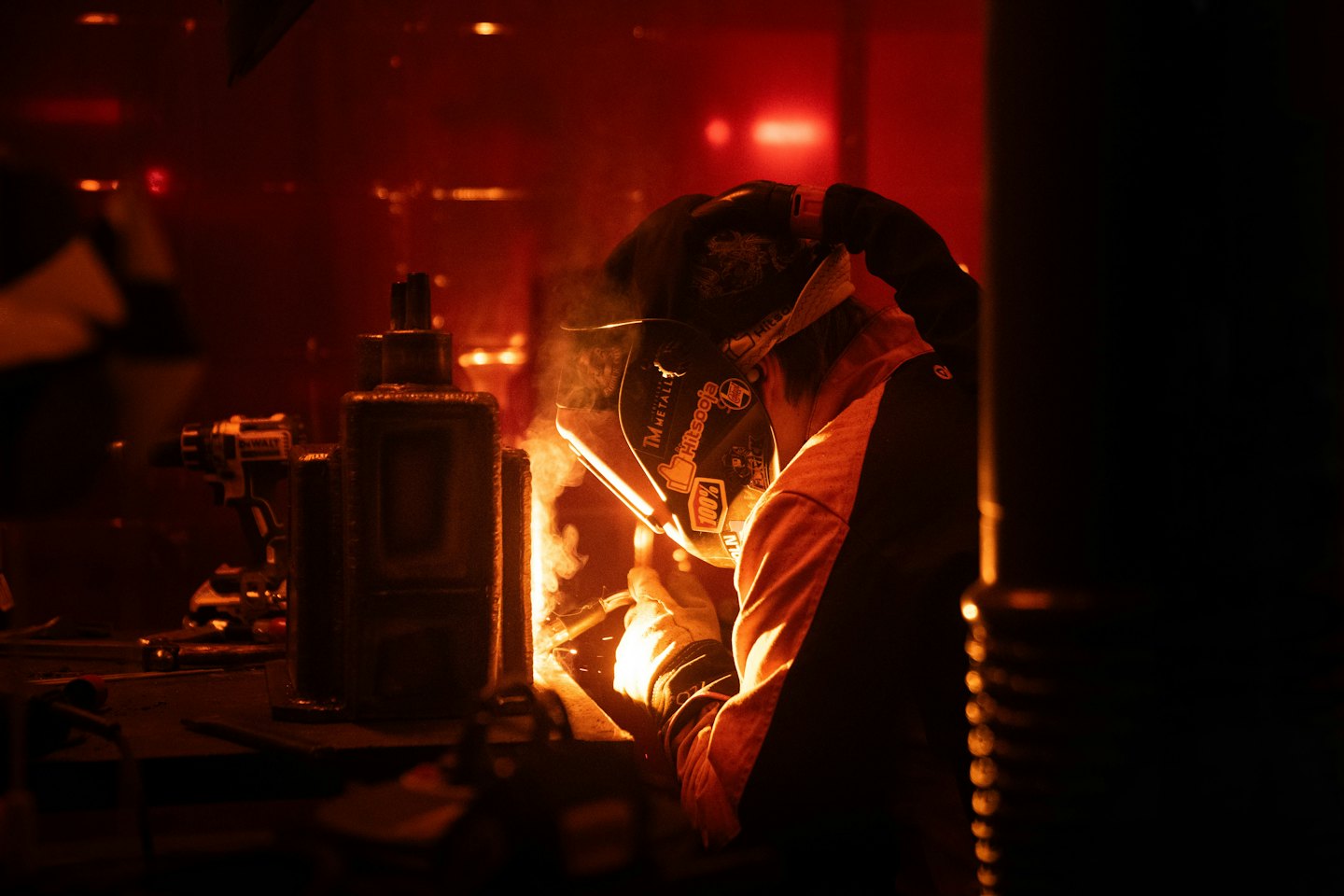 Welder in mask and gloves sparks metal.