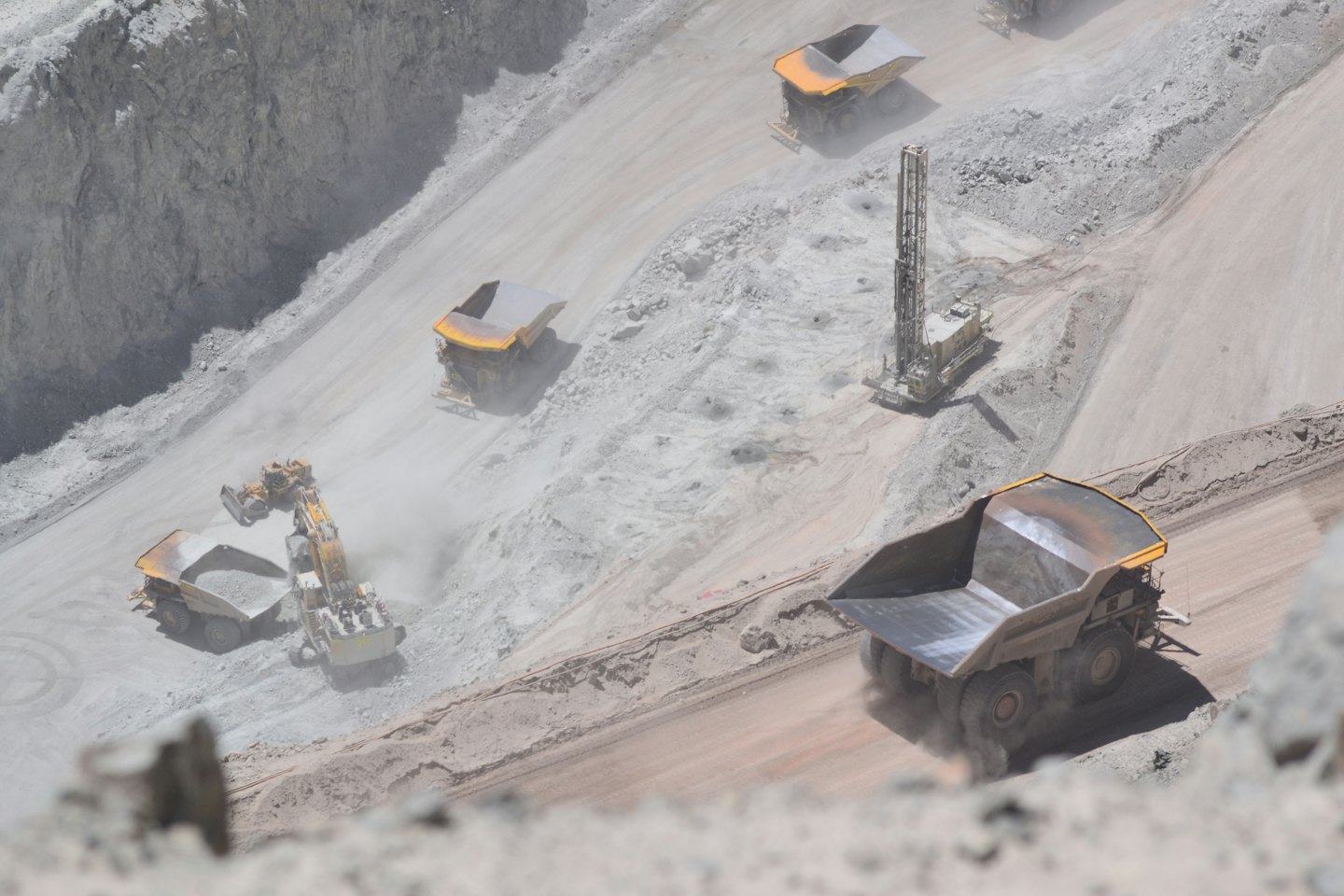Heavy machinery operates on dusty levels of an open-pit mine.
