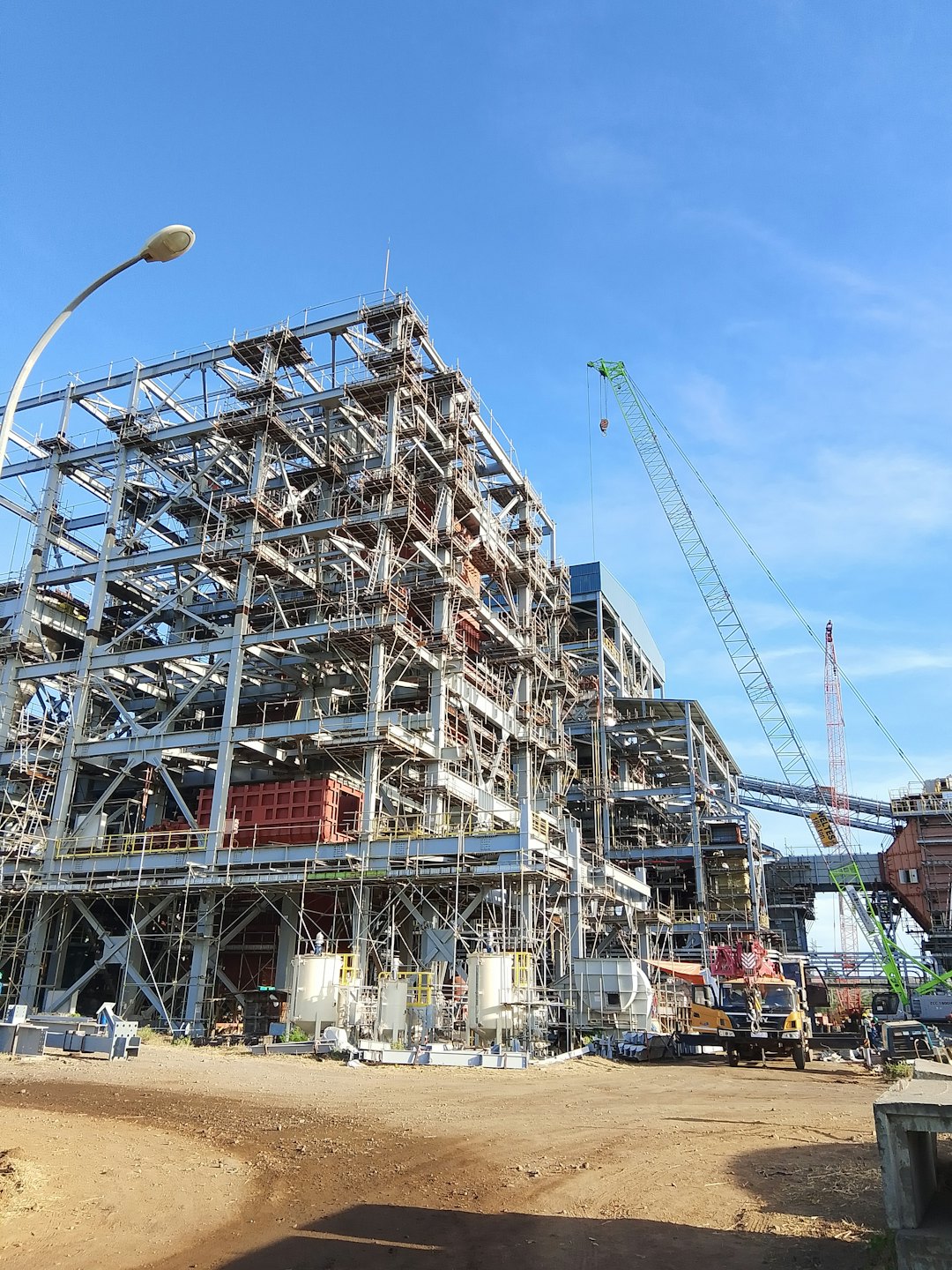 Construction workers build a large steel framework structure on site.