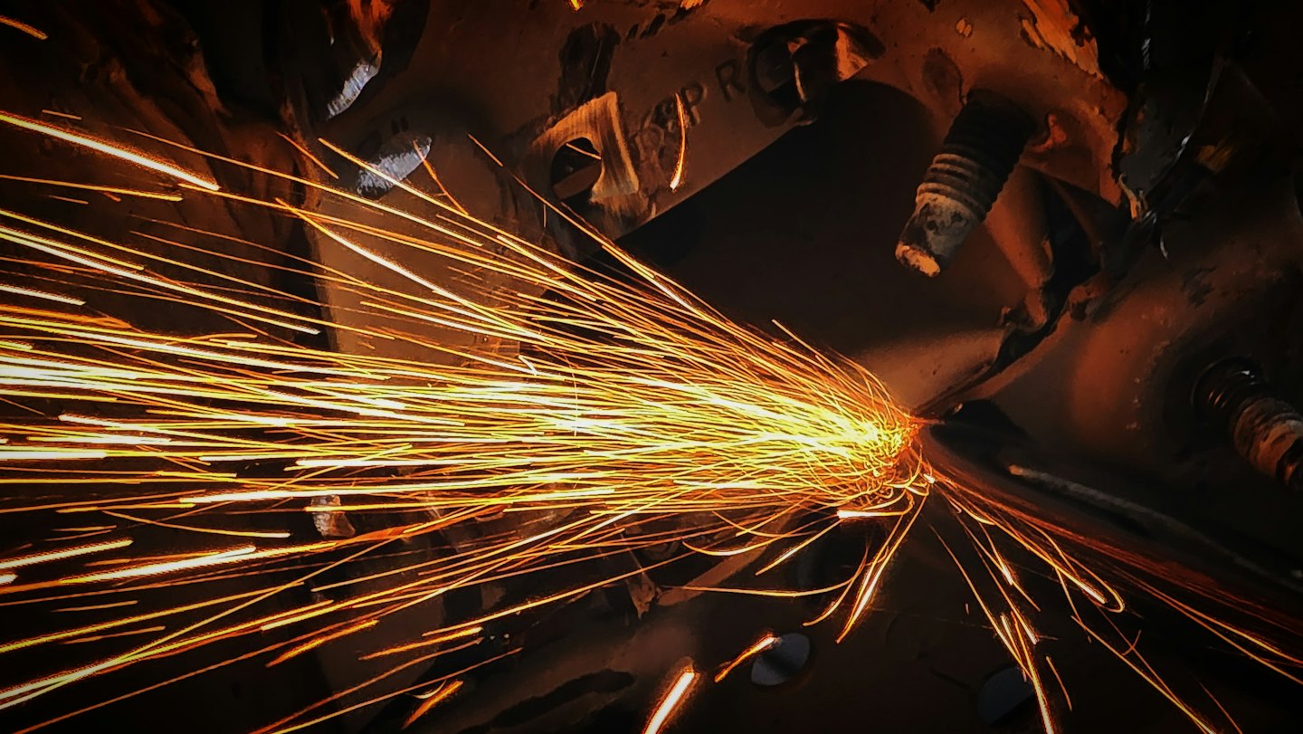 Orange sparks fly from metal on a dark surface.